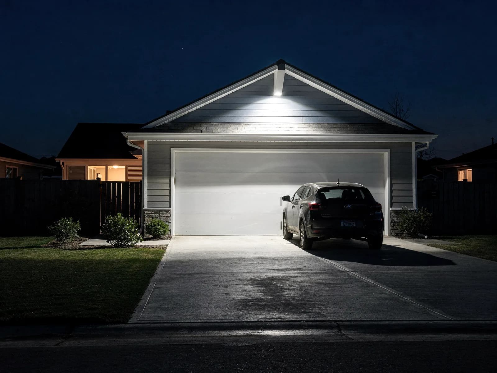 A bright exterior flood light on a gable washing a home's driveway and garage door with white light at night in Salisbury.