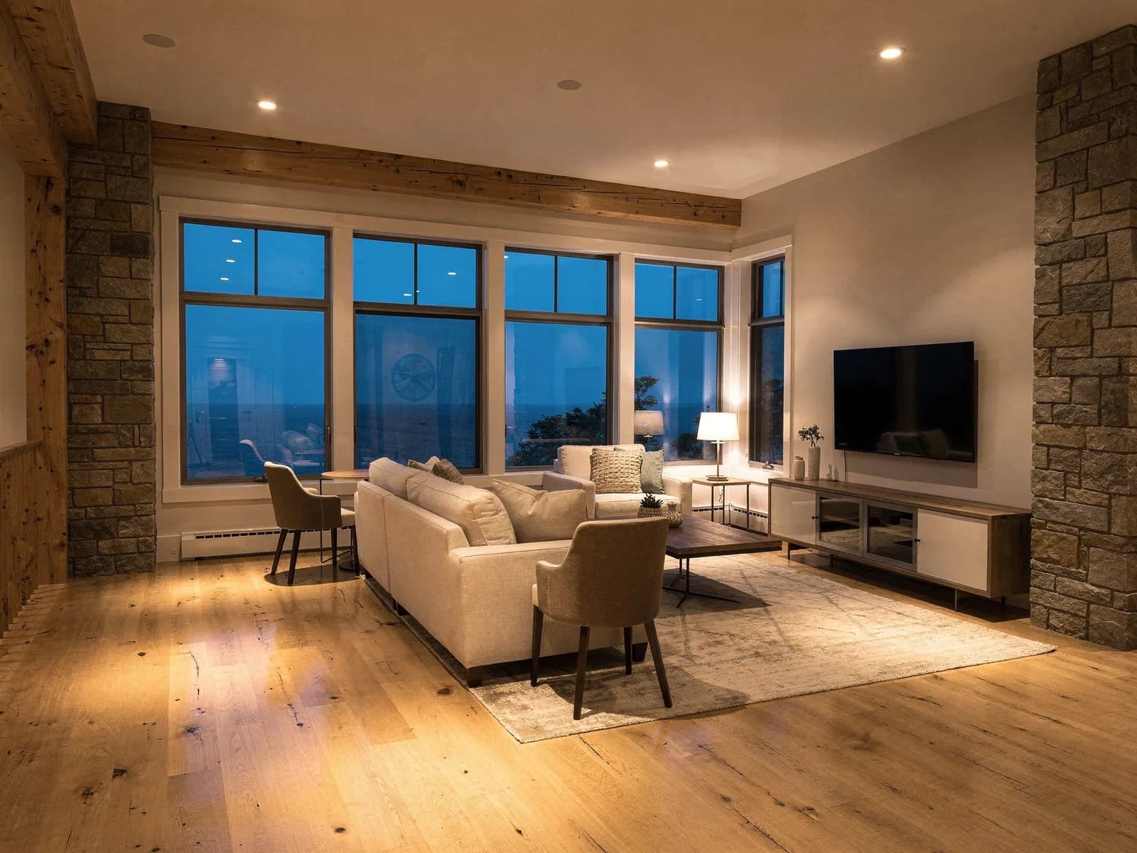 A finished living space lit by evenly placed recessed ceiling lighting at dusk in a modern New Hampshire home.