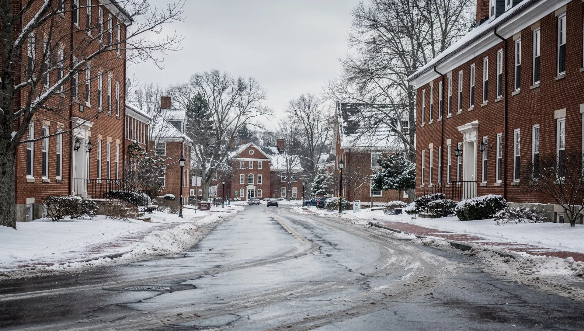A snow-lined street of red-brick Georgian academic buildings near the University of New Hampshire in Durham on an overcast winter day.